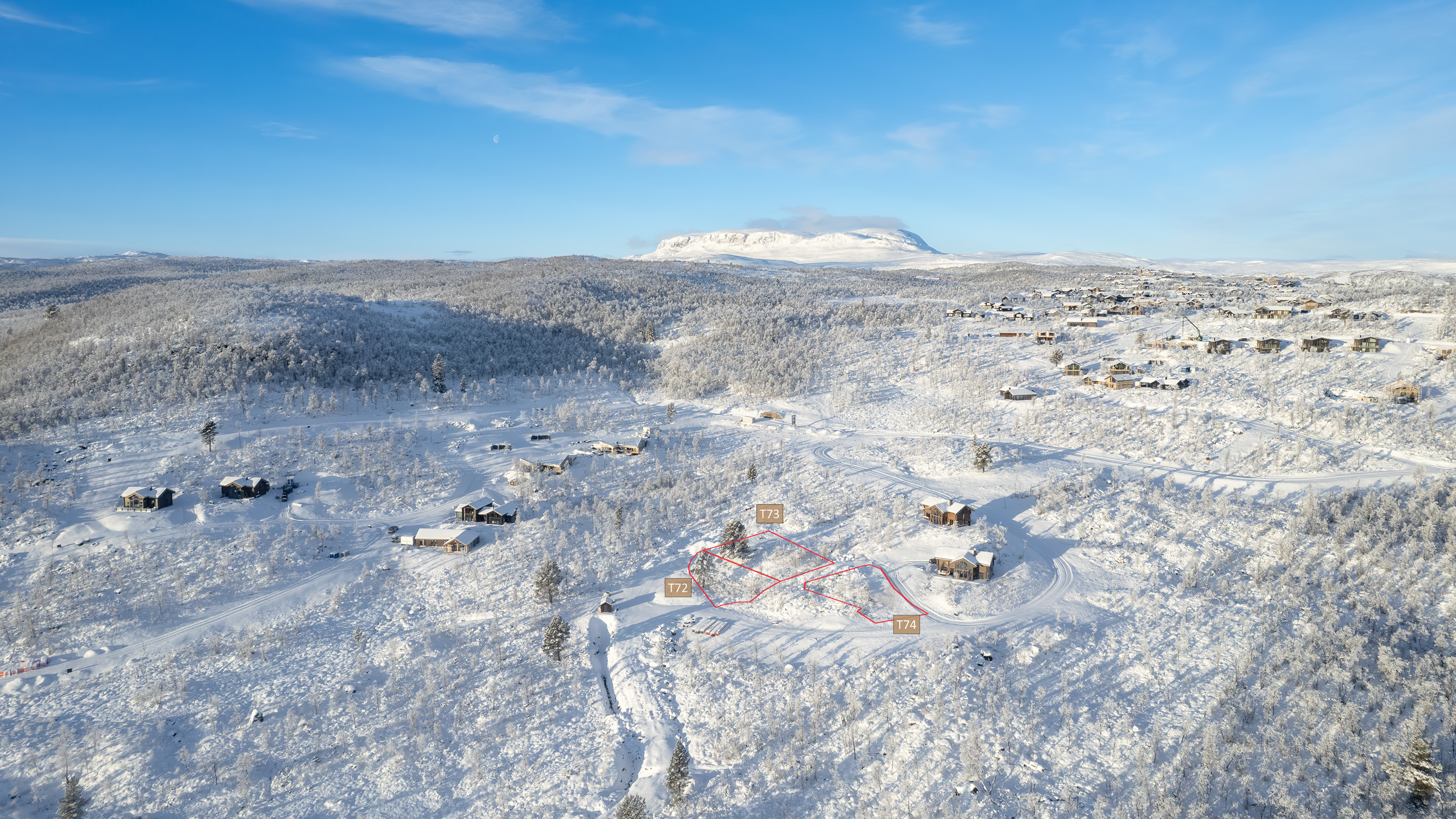 Drone bilde over Solhovda på Geilo, vinter landskap over hyttefelt, fjell og skoger, med fjellet Hallingskarvet i horisonten. Med merking av tomter på Solhalle til salgs.